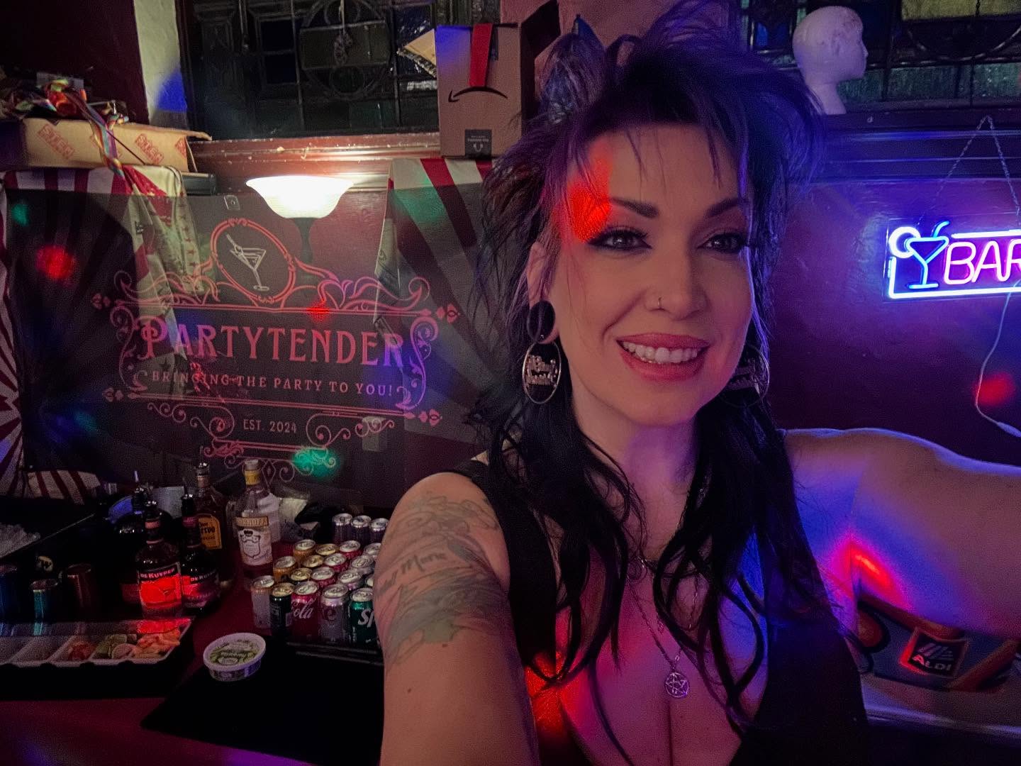 Close-up of Mandi behind the bar under the neon BAR sign